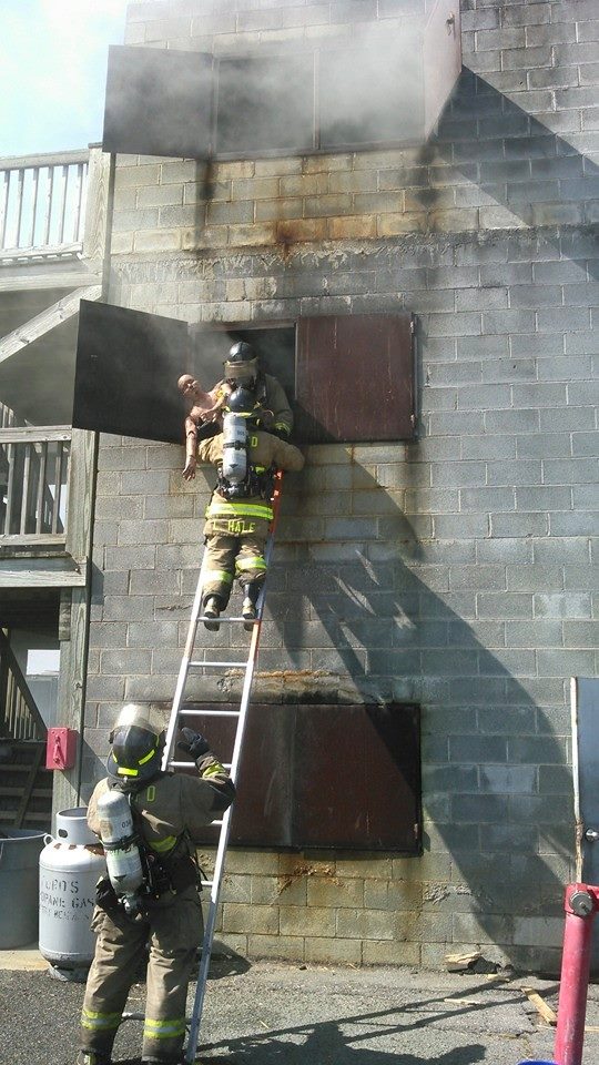 Training Exercise on a Ladder while a Firefighter Holds a Dummy