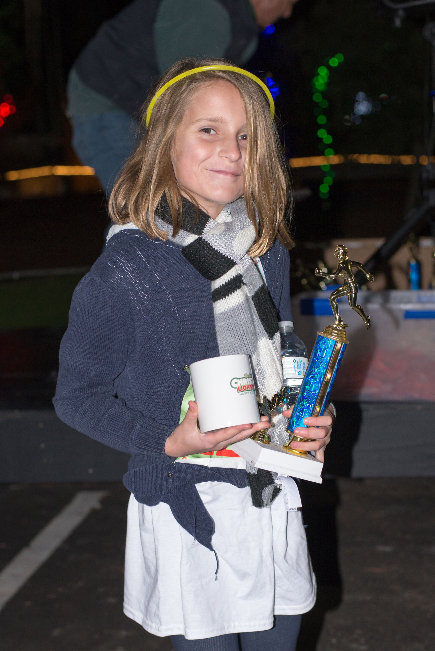 Child Holding a Mug and Trophy with a Glow Headband