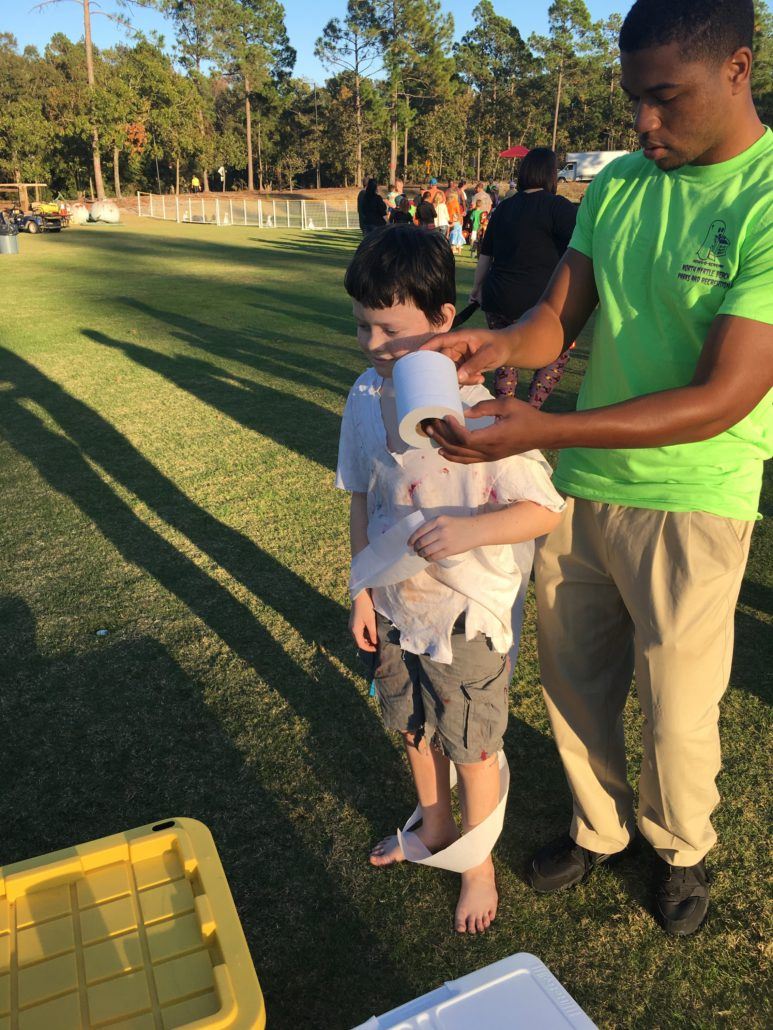 Child being wrapped in toilet paper at the Mummy Wrap